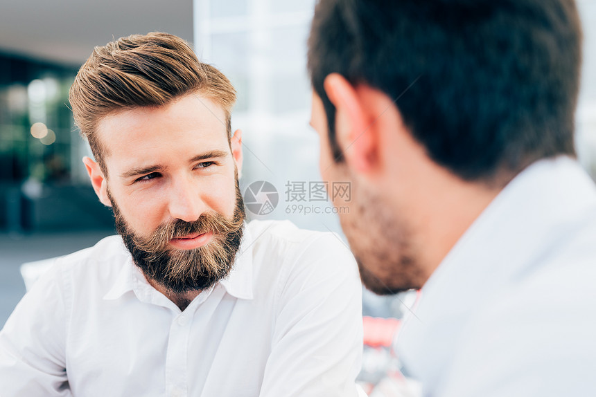 年轻漂亮的白种人留着胡子的男人与同事交谈的肖像图片