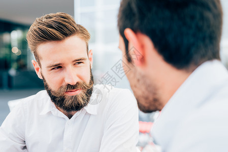 年轻漂亮的白种人留着胡子的男人与同事交谈的肖像图片