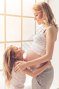 可爱的小女孩抱着她美丽的怀孕妈图片