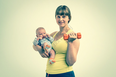 快乐的年轻女士在分娩后用哑铃加强体力图片