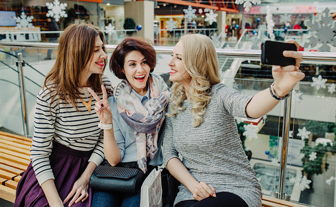 三个女友在商场新年购物中休息在智能手图片