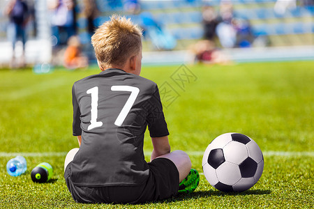 男孩坐在足球赛场上图片