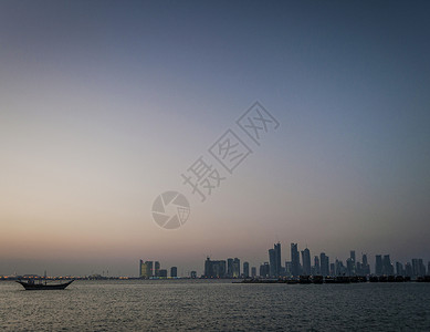 多哈城市摩天大楼城市的天线景色和单桅帆船在日图片