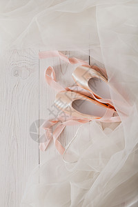 带缎和雪纺芭蕾舞短裙的新款足尖鞋铺在白色质朴的时髦木头上图片