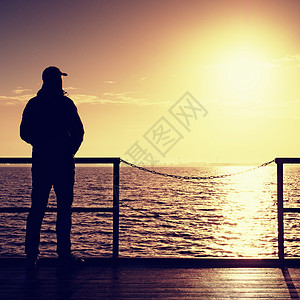 高个子站在摩尔木板上望着大海向太阳飞去空码头图片