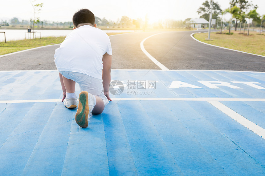 健康和自信的胖男孩在开始位置准备跑步的背面孩子运动员即将在明亮的阳图片