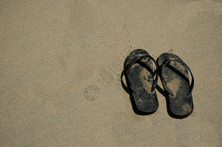 沙滩上的黑色沙滩拖鞋背景图片