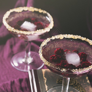 两杯鸡尾酒和浆果紫色背景的浪漫约图片