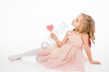 穿着粉红裙子的可爱小女孩拿着心型棒糖图片