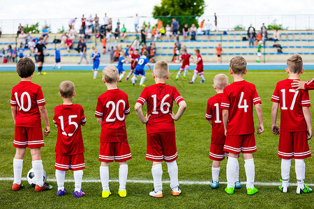 男孩玩足球比赛儿童队青年队在一起儿童足球比赛板凳上的儿童足球员与教练图片