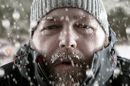 冰冷的人站在暴风雪中试图取暖图片