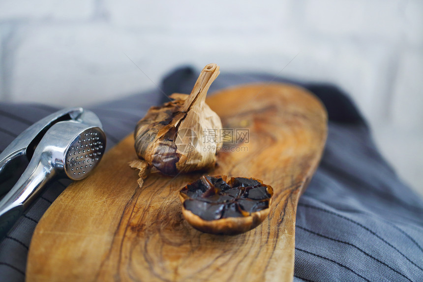 木质背景中的黑蒜鳞茎和丁香图片