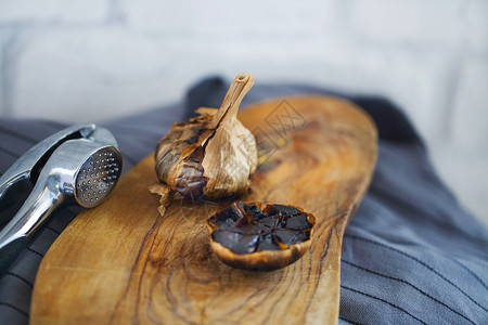 木质背景中的黑蒜鳞茎和丁香图片