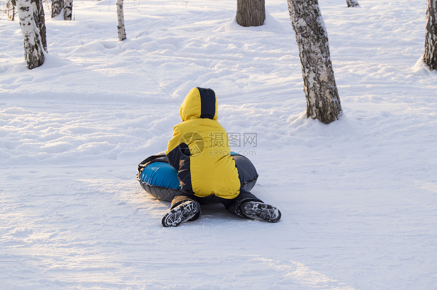 快乐的男孩滑倒在从冬季公园图片