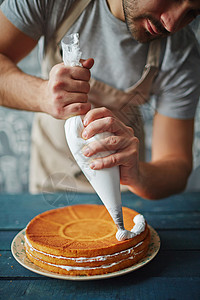 男人用生奶油装饰节日蛋糕图片
