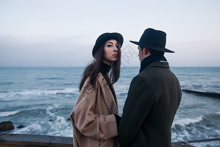 冬季大衣和帽子中时髦的情侣站在海边阳图片