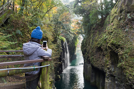 女使用手机在高原峡谷拍照的妇女Takachiho图片