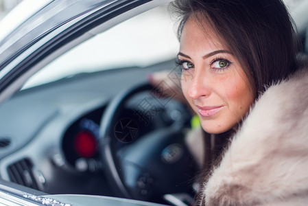 坐在车里的皮大衣微笑的女人冬天图片图片