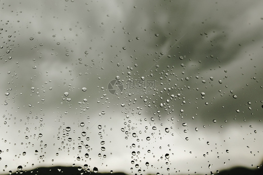 灰色云层背景的窗玻璃上的雨滴图片