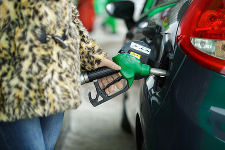 女在冬季关头的加油站将汽油图片