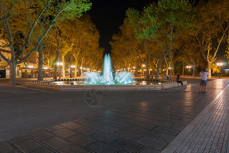 法国蒙彼利埃城市和建筑广场末端长期接触的长夜露天喷泉和树木直线图片