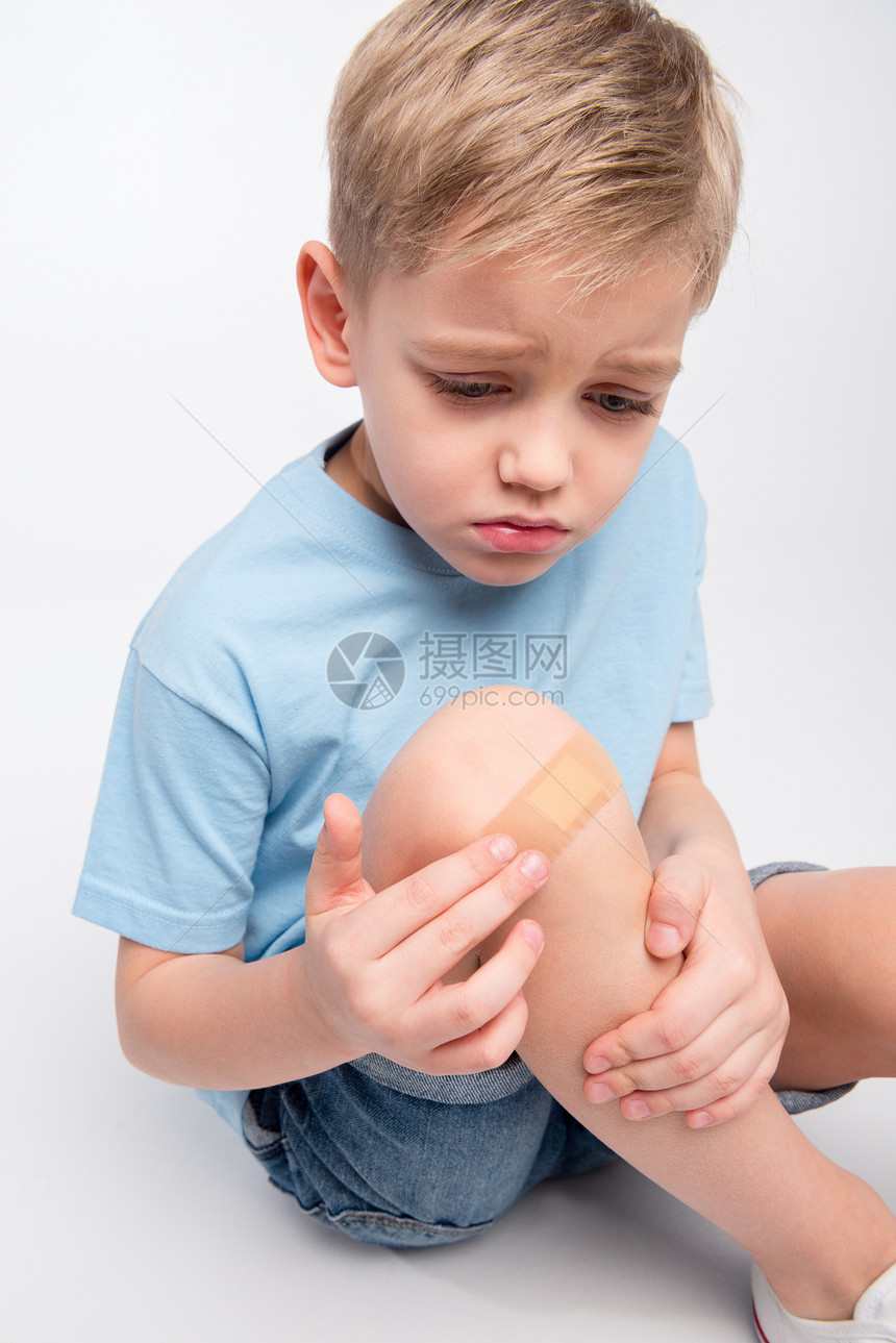 可怜的小男孩受伤膝盖上有缝合的伤痕坐图片