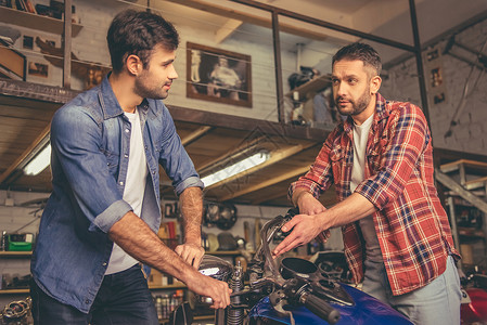 帅哥在修理车店修摩托车时说话图片