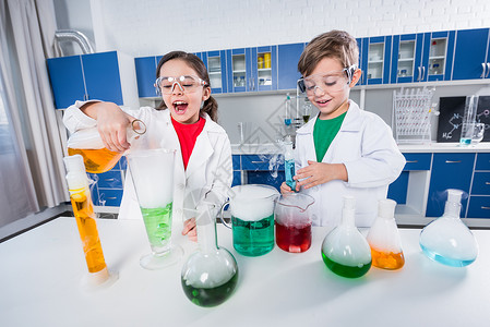 兴奋的孩子们穿着实验室外套和防护眼镜在化学图片