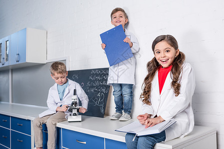 2名身着白大衣的男女儿童坐在化学实背景图片
