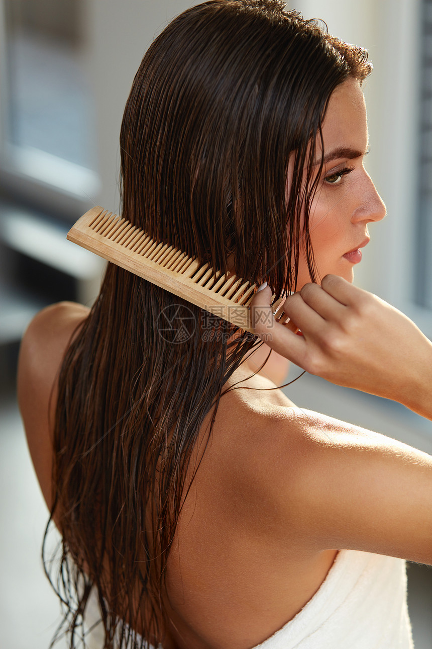头发护理美丽的女孩在沐浴理发后的特写镜头健康直棕色的头发年轻女子用木梳理她湿漉的长发健康和美丽的概念图片
