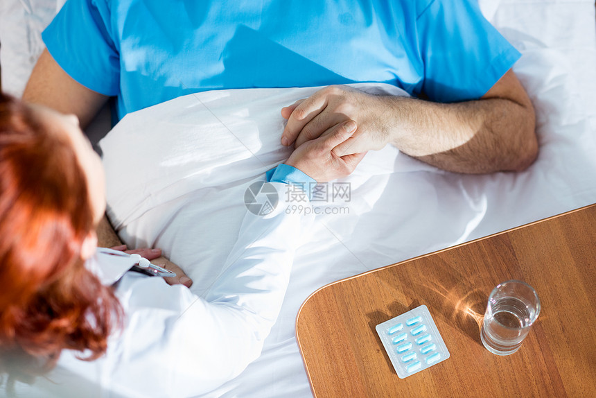 将男病人的手握在医院床上的女医生图片