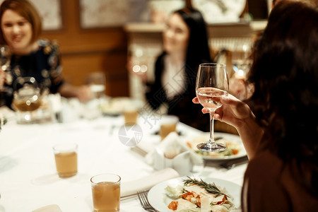 在餐厅庆祝奢华节日时拿着香槟和敬酒的女士举图片