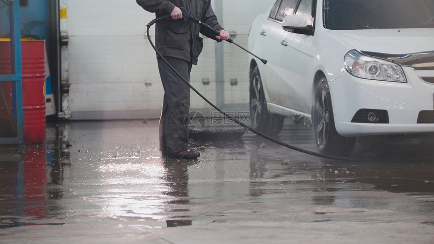 汽车服务工人正在用水管和远光洗车图片