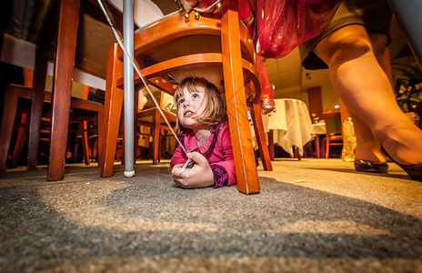 可爱的小女孩爬到椅子下面在婚礼招图片