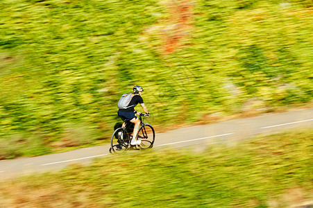 现代快速运动车骑脚踏车攀登山丘在清洁环境绿林的温暖阳光明媚日图片