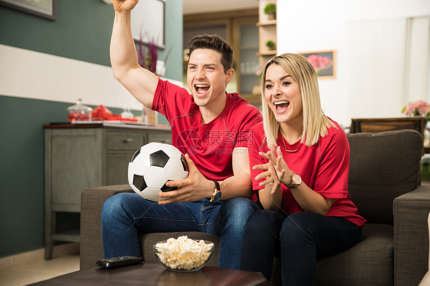 在家看足球比赛时看着一对帅美的年轻夫妇看起来图片