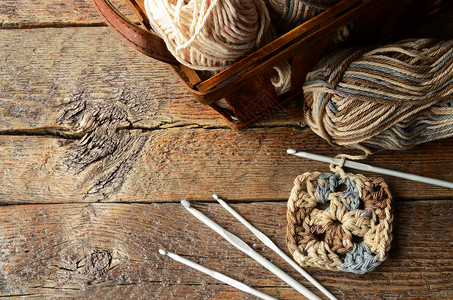 在旧木制桌顶上有一幅关于编织线编织钩和图片