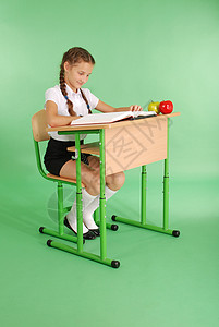 身着校服的女孩坐在书桌边看一本关于绿图片