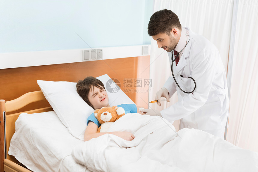 害怕的小男孩与泰迪熊Teddy熊躺在医院床上图片