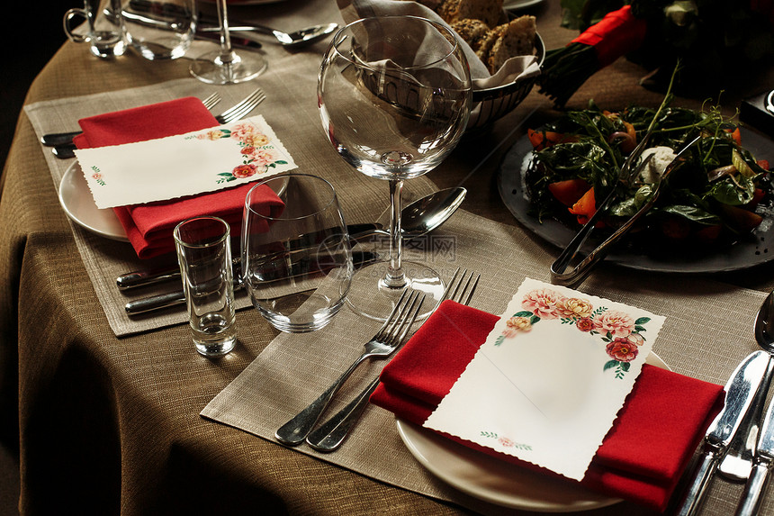 豪华葡萄酒杯和银餐具贴在有红餐巾图片