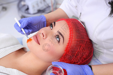 美丽的年轻女正在接受面部皮肤治疗有刷子的神经医生在图片