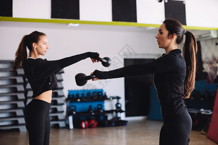 健身女壶铃锻炼在健身房两名妇女图片
