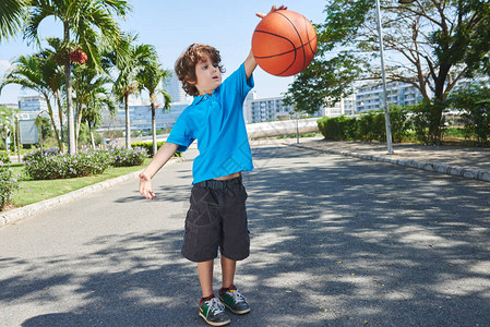 有趣的小篮球选手在阳光明媚的公园里带着棕榈树背景图片