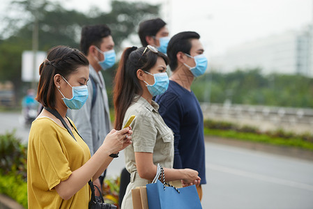 两名身戴防护面具的亚裔妇女和三名亚裔男子在现代城市路边站图片