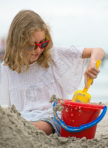 小女孩在沙滩上玩沙子图片