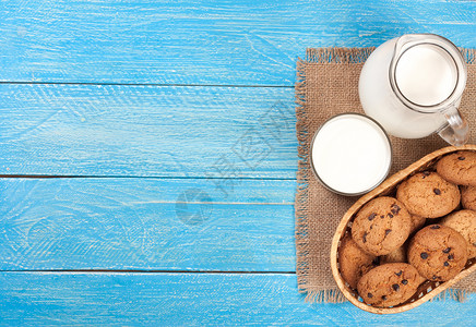 水罐和一杯牛奶和燕麦饼干放在一个柳条篮子里图片