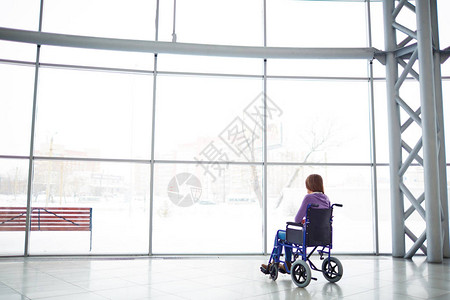 残疾妇女坐在购物商场轮椅上看大窗户图片