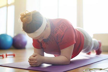在日光健身工作室做瑜伽垫的年轻肥胖女肖像图片