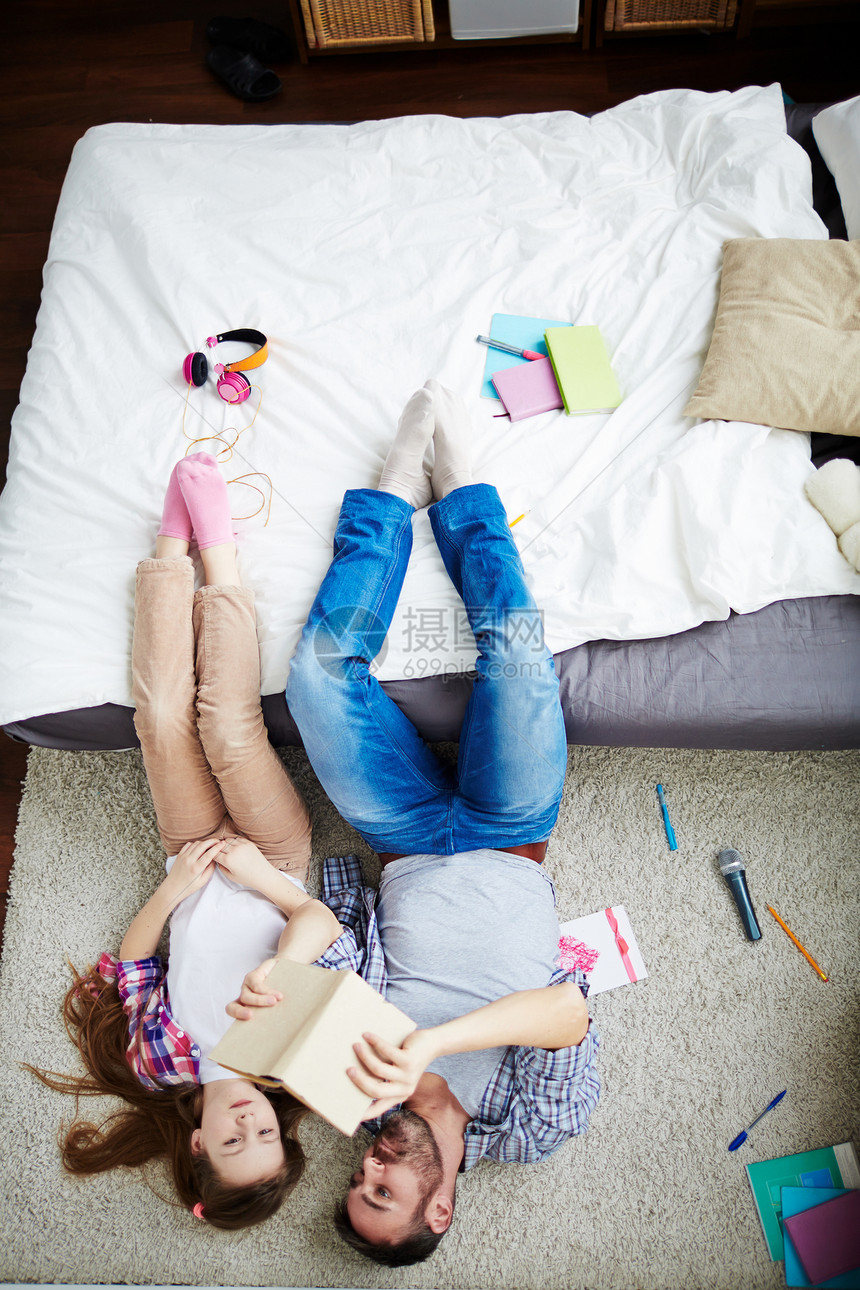 漂亮的小女孩和她长胡子的爸读着多彩百科全书在地板上放松图片