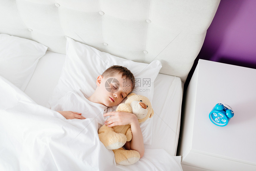 小男孩睡在床上抱着他最爱吃的泰迪熊图片